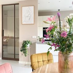 a vase filled with flowers sitting on top of a wooden table next to a kitchen