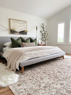 a large bed sitting on top of a wooden floor next to a white wall and window