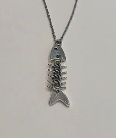 a silver necklace with a fish on it's side and the word love spelled in cursive letters