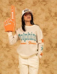 Miami Dolphins x Duvin "A Flippin Good Time" Limited Collection *Knit is exclusive to Duvindesign.com and Dolphins Stadium This knitted vintage Miami Dolphins crewneck takes you back to the era of legends. Crafted from a cozy knit blend, it's got that perfectly worn-in feel, like it’s been passed down from generations of die-hard fans. Knitted with high-quality materials. Relaxed, comfortable fit and perfect layering option with the rest of the Duvin x Dolphins collection. Mid-weight vintage kni Retro Knit Sweater With Ribbed Cuffs, Retro Knit Tops With Ribbed Cuffs, White Retro Sweater With Letter Print, Retro White Sweater With Letter Print, Retro Crew Neck Knit Top, Retro Knit Top With Graphic Print, College Crew Neck Knit Sweater, Cream Graphic Print Crew Neck Sweater, Cream Crew Neck Sweater With Graphic Print