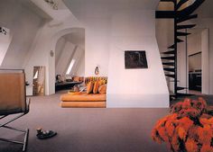 a living room filled with furniture next to a spiral stair case in an attic style home