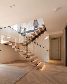 there is a stair case in the middle of this room with wood floors and glass railings