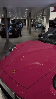 a red sports car in a showroom with other cars