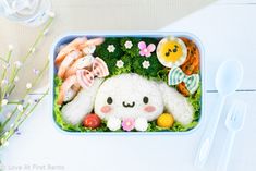 a bento box filled with sushi, vegetables and meats in the shape of an animal