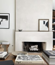 a living room filled with furniture and a fire place covered in books on top of a hard wood floor