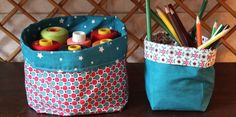 two bags with pencils, tape and scissors in them sitting on a table next to each other