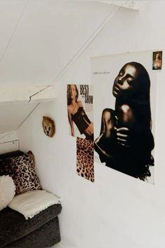 a room with posters on the wall and a couch in front of it that has a leopard print pillow