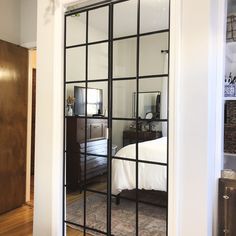 an open door leading to a bedroom with a bed and dresser in the background on a hardwood floor