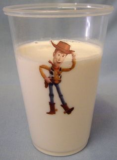 a glass filled with milk and a cartoon character on the side, sitting on a table