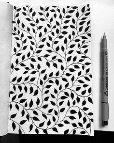 a black and white photo of a leafy pattern on a notebook next to a crayon marker