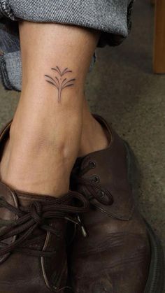 a woman's foot with a small flower tattoo on her left ankle and the bottom part of her shoe