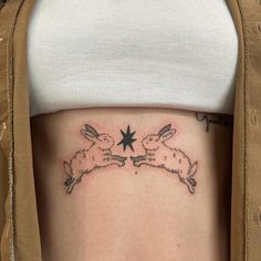 a woman's stomach with two rabbits and a star tattoo on the left side