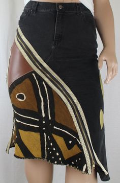 "Handcrafted One-Of-A-Kind Upcycle jean skirt This Lucy Roots Denim handcrafted one-of-a-kind upcycle jean skirt, is a striking piece of Afrocentric apparel that embodies the essence of Black culture clothing and Diasporic fashion. Constructed from thrifted jeans, this plus size pencil skirt is pieced with African Mud Cloth and genuine leather. Decorative gold & white braided trim add depth and texture. Featuring a shimmering 19\" Gold Vinyl Ankh applique that pays homage to African heritage fashion with its ancient Egyptian symbolism of life. Function meets style with front and side seam metal zippers so you can choose to be modest....or not. All seams and raw edge hem are serge finished for durability and quality craftsmanship. Included with the skirt is a one yard cut piece of a coordin King Jean Skirt, Black And Gold Plus Size, Upcycle Jeans Skirt, Thrifted Jeans, Plus Size Pencil Skirt, Denim Diy Clothes, Mode Hippie, Culture Clothing, Diy Vetement