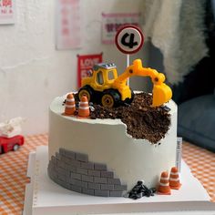 a cake with construction vehicles on top of it and a road sign in the background