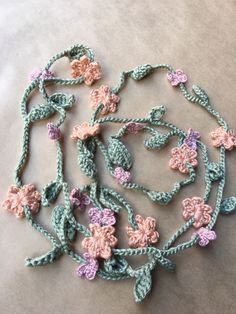 crocheted flowers and leaves are arranged in the shape of a heart on a table