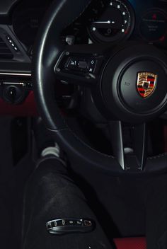 the steering wheel and dashboard of a porsche car with red stitching on it's dash