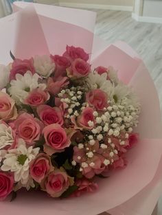 a bouquet of pink and white flowers sitting on top of a paper wrapper in a room