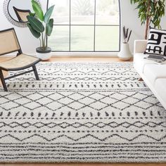 a living room area with a white couch and black and white rug on the floor