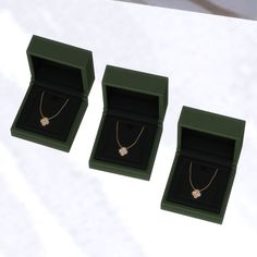 three green boxes with necklaces in them