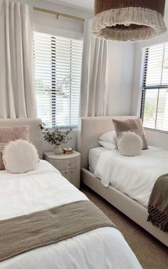 two twin beds in a bedroom with white walls and beige bedding, one has pillows on the headboard