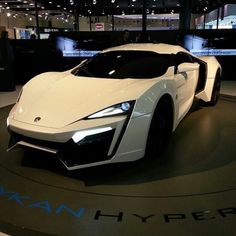 a white sports car is on display at an auto show