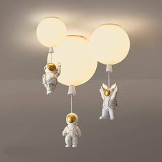 an astronaut themed ceiling light fixture with three lights attached to it and two astronauts on each side