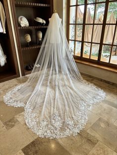 a wedding dress is on display in front of a window with the veil draped over it