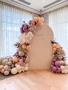 an arch made out of balloons and flowers is displayed in the middle of a room