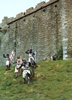 men dressed in medieval clothing standing on the side of a castle