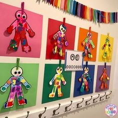 there are many colorful paper dolls hanging on the wall