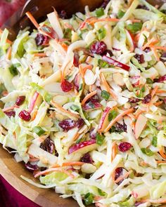 a salad with carrots, cranberries and lettuce in a wooden bowl