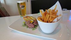 a white plate topped with french fries and a sandwich next to a glass of beer