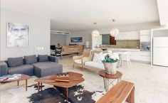 a living room filled with furniture and a large painting on the wall above an open kitchen