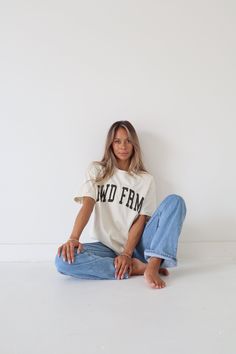 a woman sitting on the floor wearing jeans and a t - shirt that says no frm