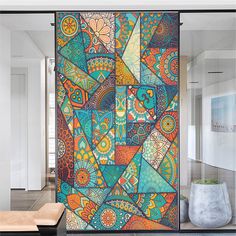 an abstract painting on the side of a glass door in a room with white walls