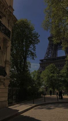 the eiffel tower towering over people walking on a sidewalk in front of it