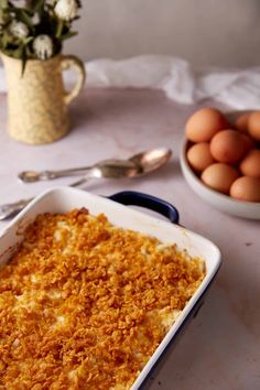 a casserole dish on a table with eggs in the bowl next to it