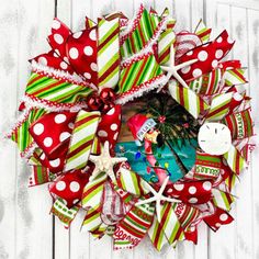 a christmas wreath with red and green ribbons, decorations and starfishs on it