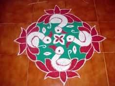 a decorated floor with red and green flowers on the ground in front of a tile wall