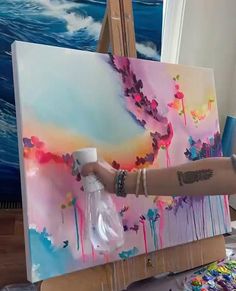 a person is painting on an easel with paint