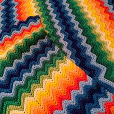 a multicolored crocheted blanket laying on top of a bed