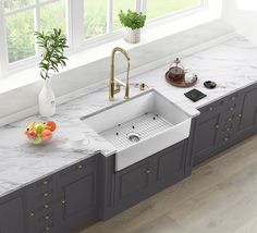 a kitchen with marble counter tops and gray cabinets, including a white double bowl sink