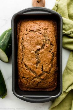 a loaf of zucchini bread sitting in a pan next to cucumbers