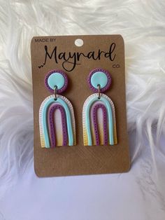 a pair of earrings that are on top of a white furnishing background with the words made by mayward