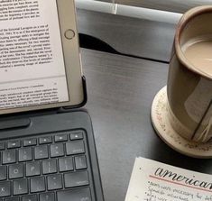 an open laptop computer sitting on top of a desk next to a cup of coffee