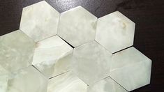 several white hexagons are arranged on a black table top, one is missing the center piece