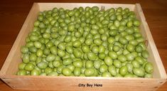 a wooden box filled with lots of green apples