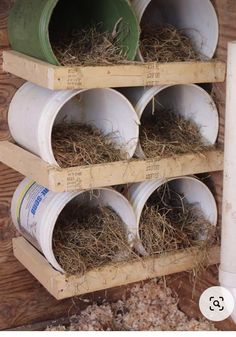 a bunch of buckets that are hanging on a wooden wall with some hay in them