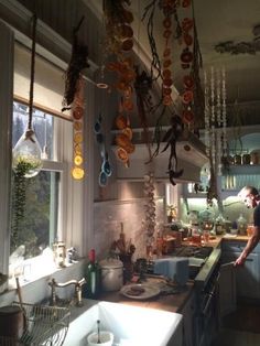 a man standing in a kitchen next to a sink and counter with pots hanging from the ceiling