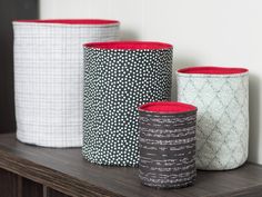 three different colored vases sitting on top of a wooden shelf